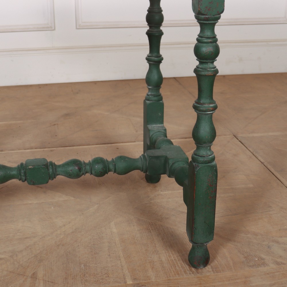 An 18th-century English lamp table featuring a dark green painted surface, single drawer with brass handles, and turned legs with lower stretchers. View IV