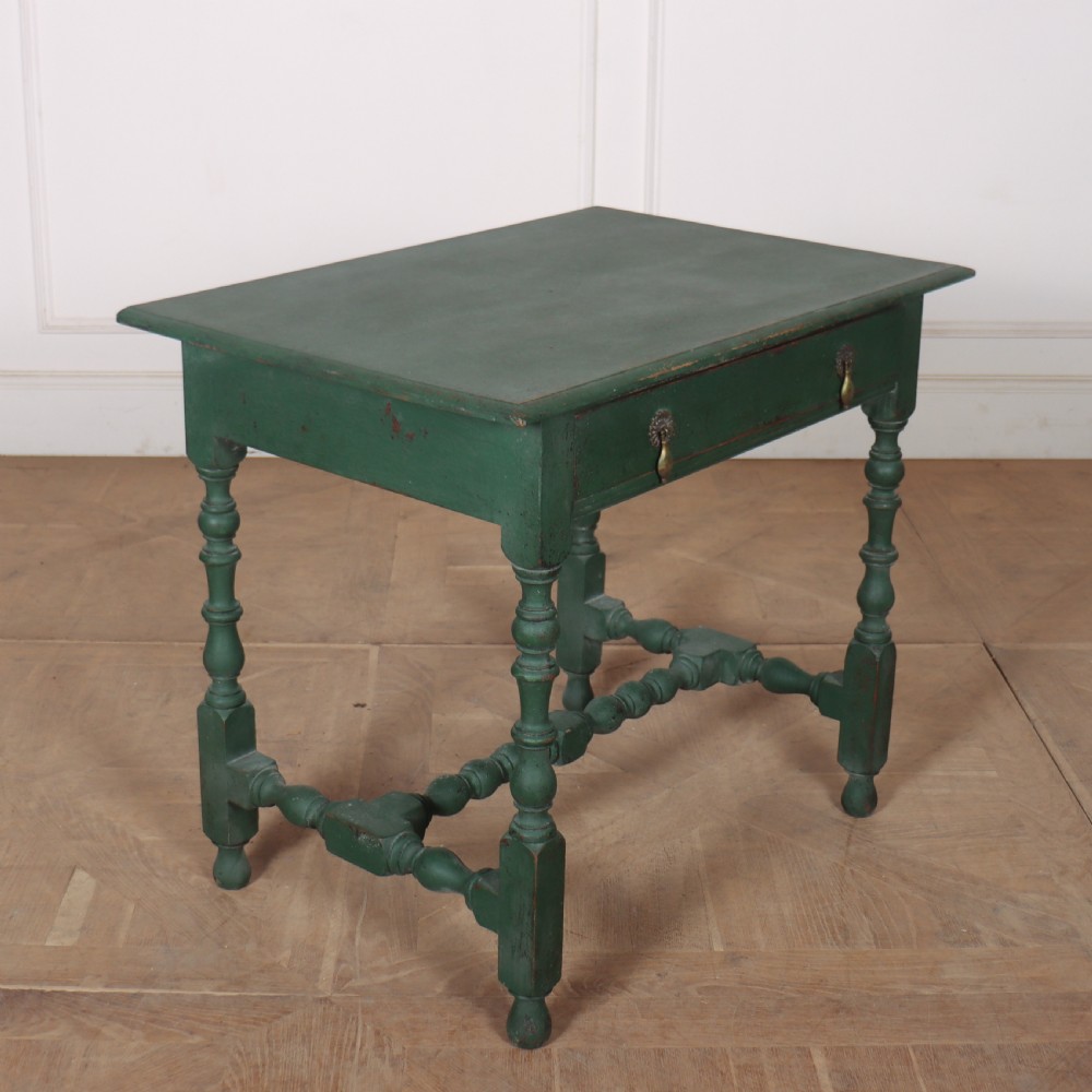 An 18th-century English lamp table featuring a dark green painted surface, single drawer with brass handles, and turned legs with lower stretchers. View VI