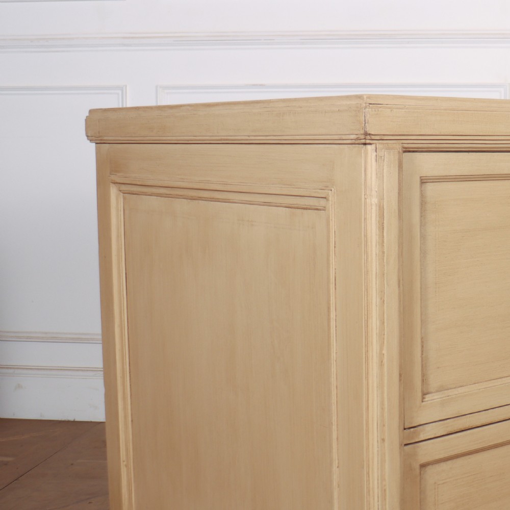 A low, wide wooden drapers chest in a neutral beige painted finish featuring four large paneled drawers with dark metal handles. View II
