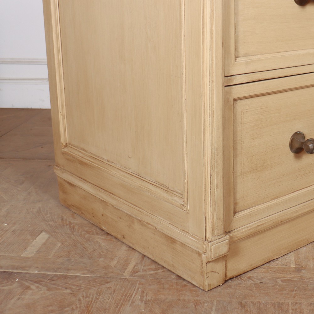 A low, wide wooden drapers chest in a neutral beige painted finish featuring four large paneled drawers with dark metal handles. View III