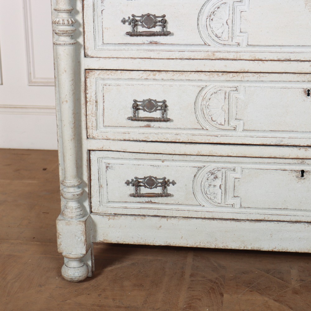 A pale grey painted antique French commode featuring carved drawer fronts, brass hardware, and turned fluted corner columns. View III