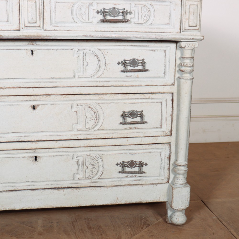 A pale grey painted antique French commode featuring carved drawer fronts, brass hardware, and turned fluted corner columns. View V