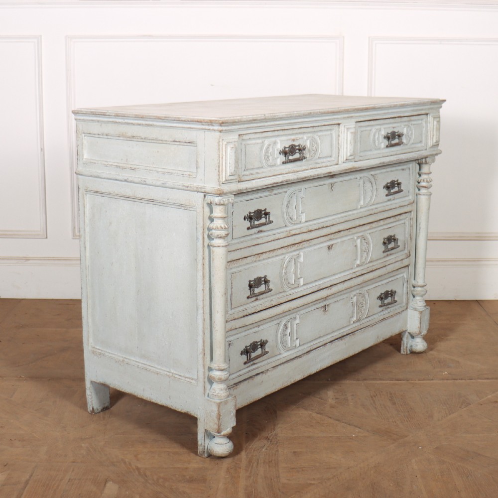 A pale grey painted antique French commode featuring carved drawer fronts, brass hardware, and turned fluted corner columns. View VII