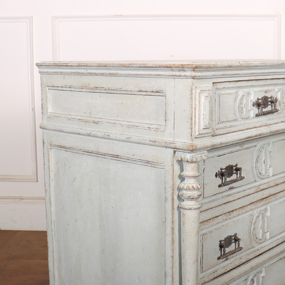 A pale grey painted antique French commode featuring carved drawer fronts, brass hardware, and turned fluted corner columns. View VIII