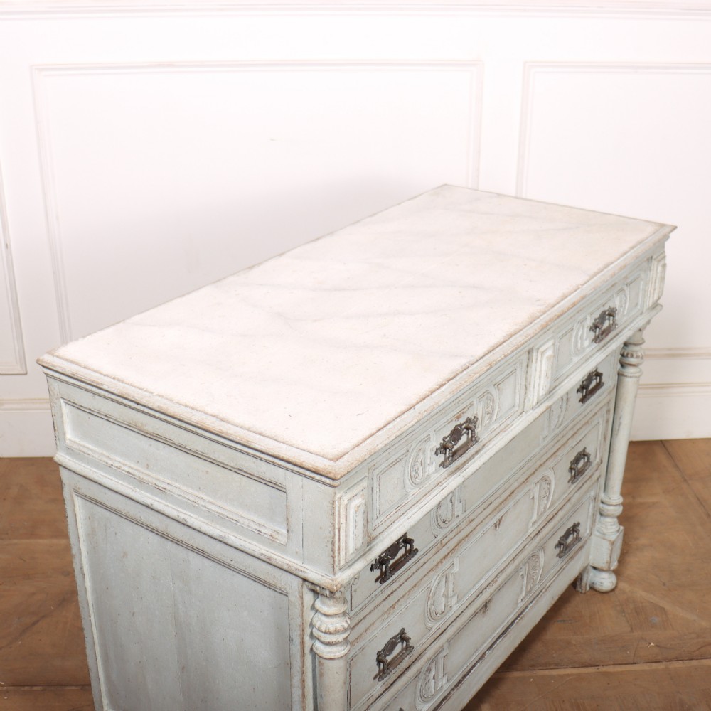 A pale grey painted antique French commode featuring carved drawer fronts, brass hardware, and turned fluted corner columns. View IX