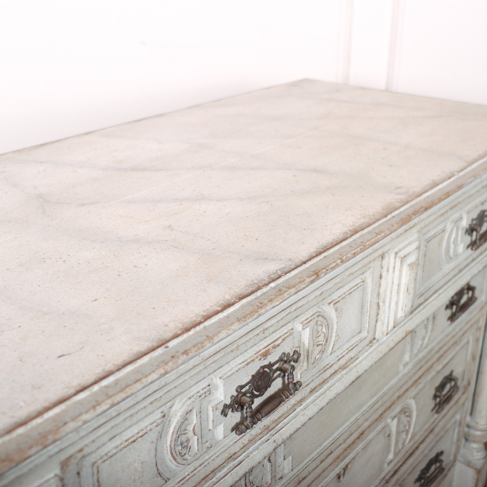 A pale grey painted antique French commode featuring carved drawer fronts, brass hardware, and turned fluted corner columns. View X