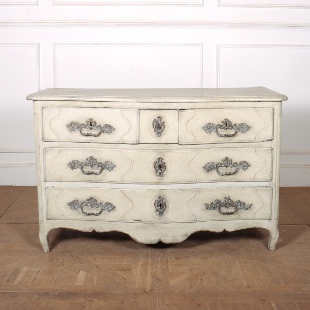 A French painted serpentine commode with three drawers, moulded panels, ornate brass handles, and short cabriole legs.