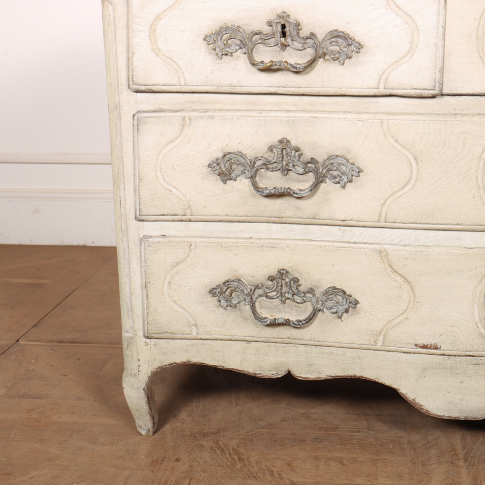 A French painted serpentine commode with three drawers, moulded panels, ornate brass handles, and short cabriole legs. View II