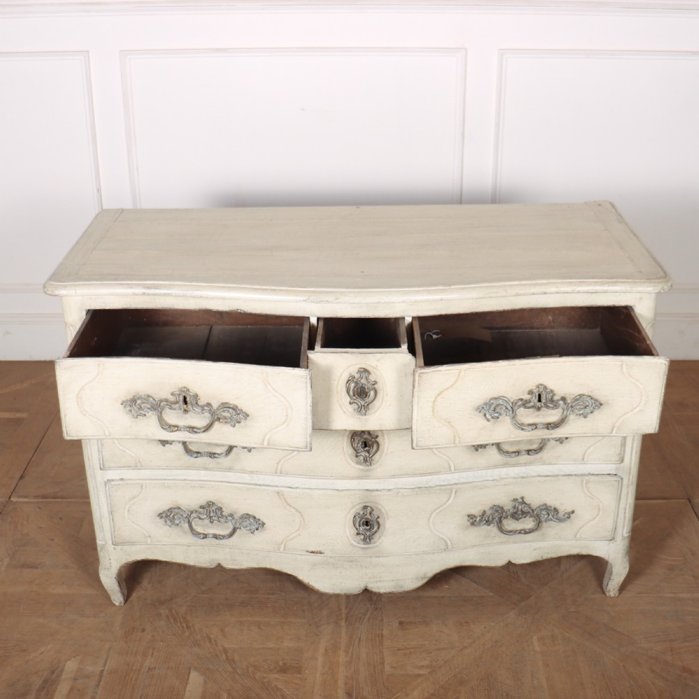 A French painted serpentine commode with three drawers, moulded panels, ornate brass handles, and short cabriole legs. View VI