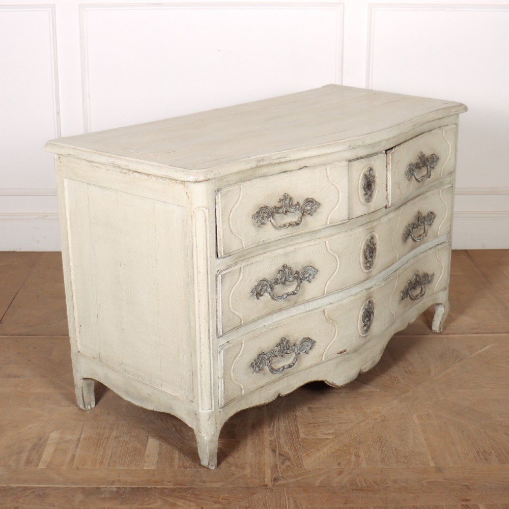 A French painted serpentine commode with three drawers, moulded panels, ornate brass handles, and short cabriole legs. View VII