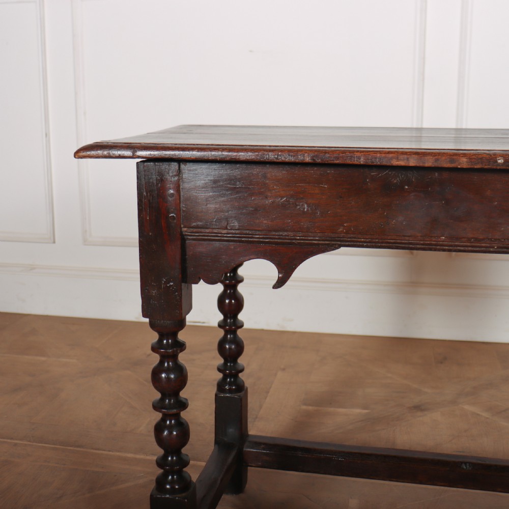An 18th-century dark oak side table with turned legs, shaped apron, and perimeter stretcher base against a light background. View II