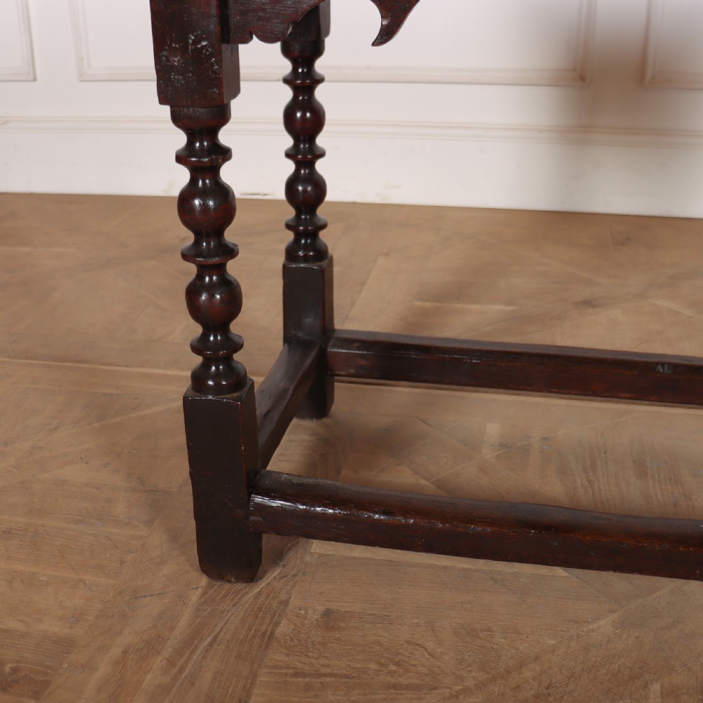 An 18th-century dark oak side table with turned legs, shaped apron, and perimeter stretcher base against a light background. View III