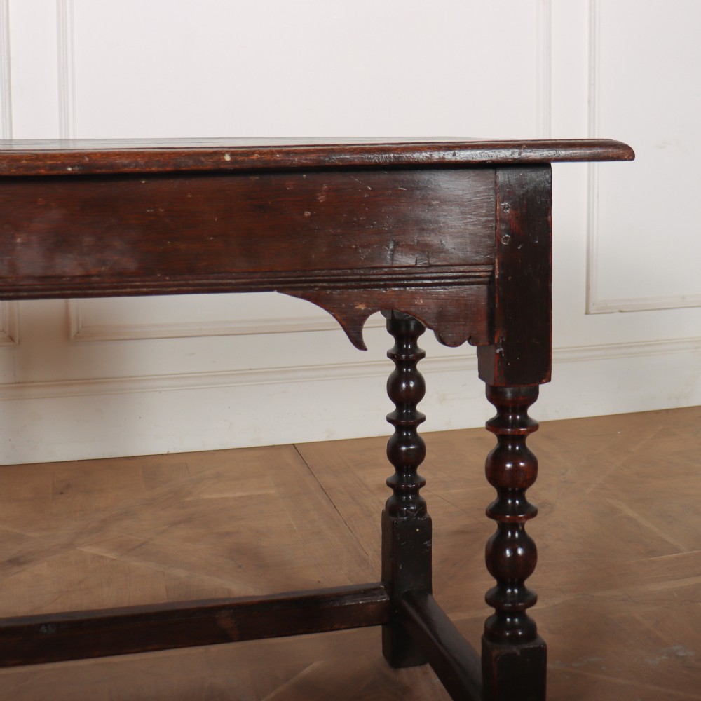 An 18th-century dark oak side table with turned legs, shaped apron, and perimeter stretcher base against a light background. View IV