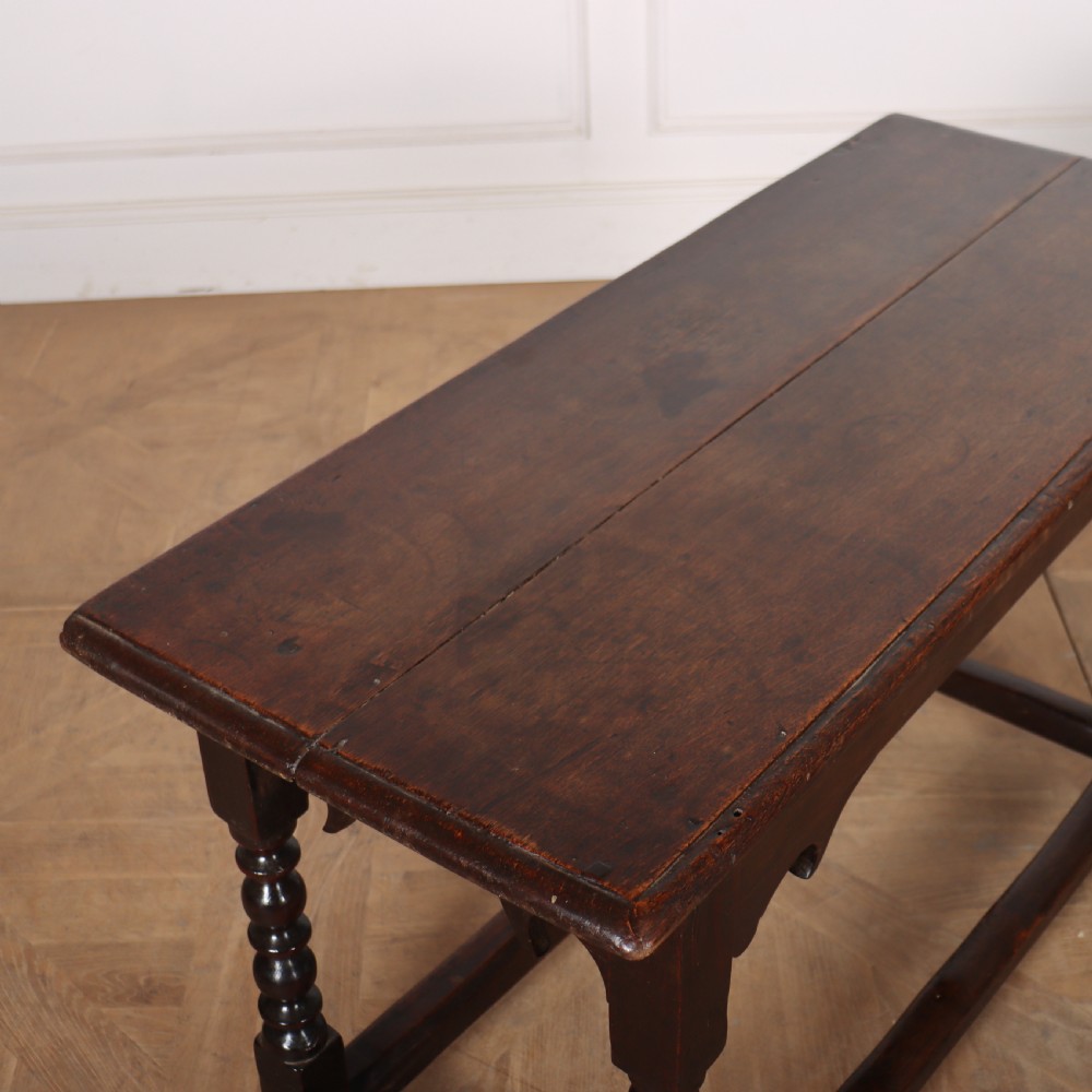 An 18th-century dark oak side table with turned legs, shaped apron, and perimeter stretcher base against a light background. View VII