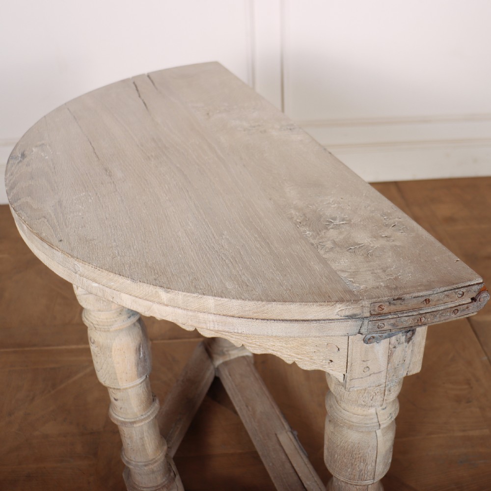 An 18th century Dutch demilune console table made from bleached oak, featuring three heavy turned legs, a scalloped apron, and a triangular low stretcher base. View VIII