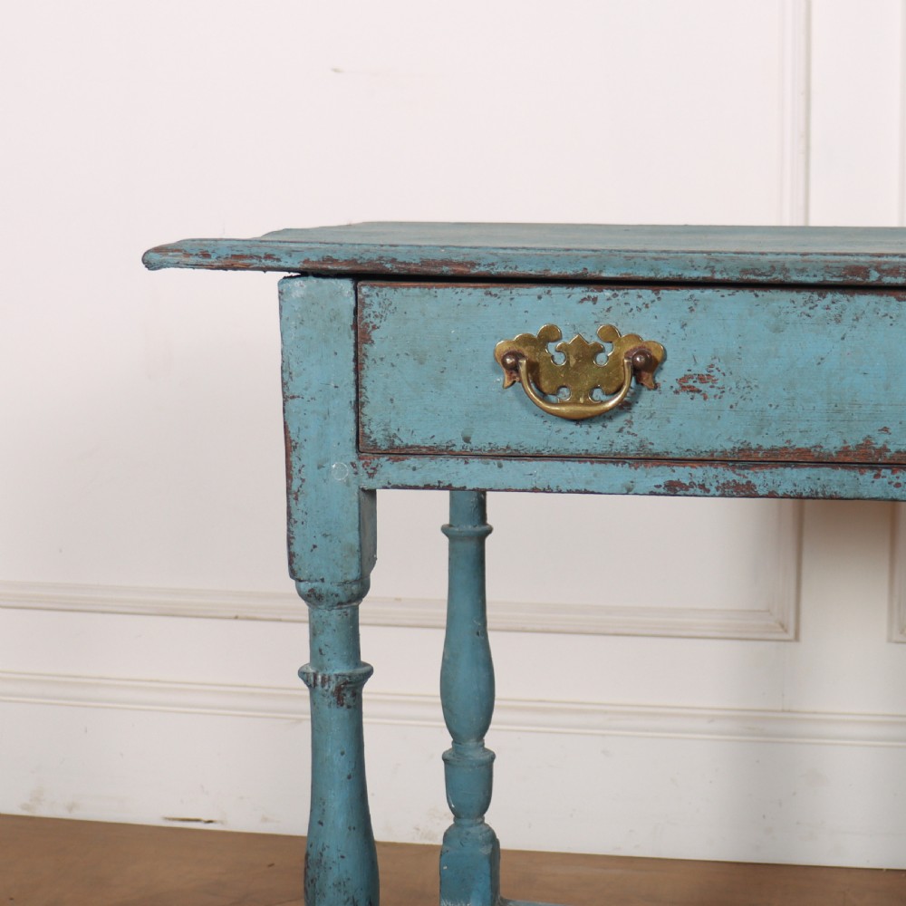 An 18th-century rectangular lamp table featuring a distressed blue painted finish, turned legs, a lower stretcher base, and a single drawer with brass handles. View II