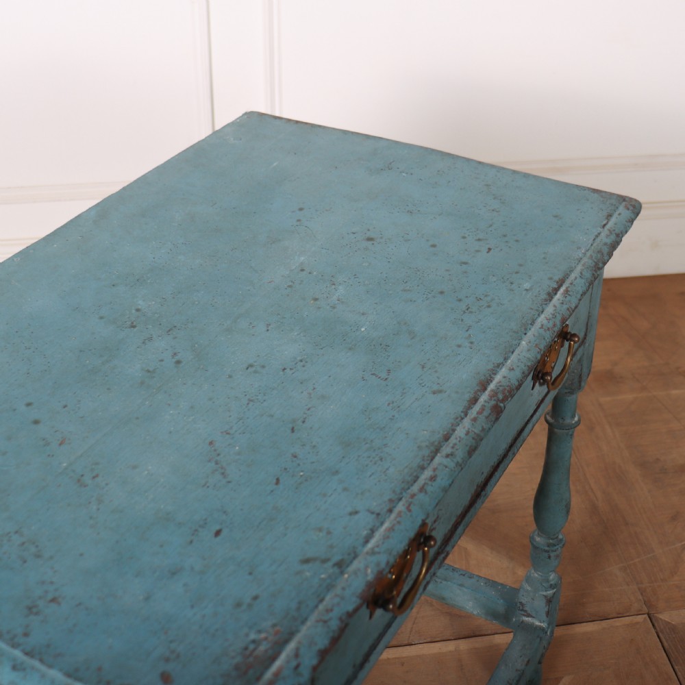 An 18th-century rectangular lamp table featuring a distressed blue painted finish, turned legs, a lower stretcher base, and a single drawer with brass handles. View VII