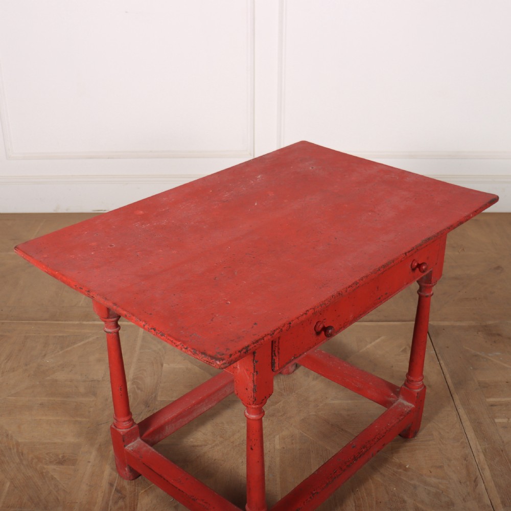 A red painted wooden lamp table featuring a single central drawer with wooden knobs, turned legs, and a lower stretcher base. View V