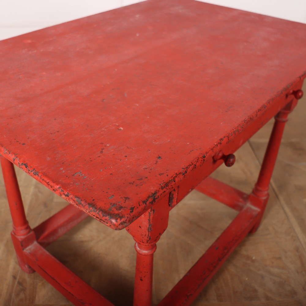 A red painted wooden lamp table featuring a single central drawer with wooden knobs, turned legs, and a lower stretcher base. View VI