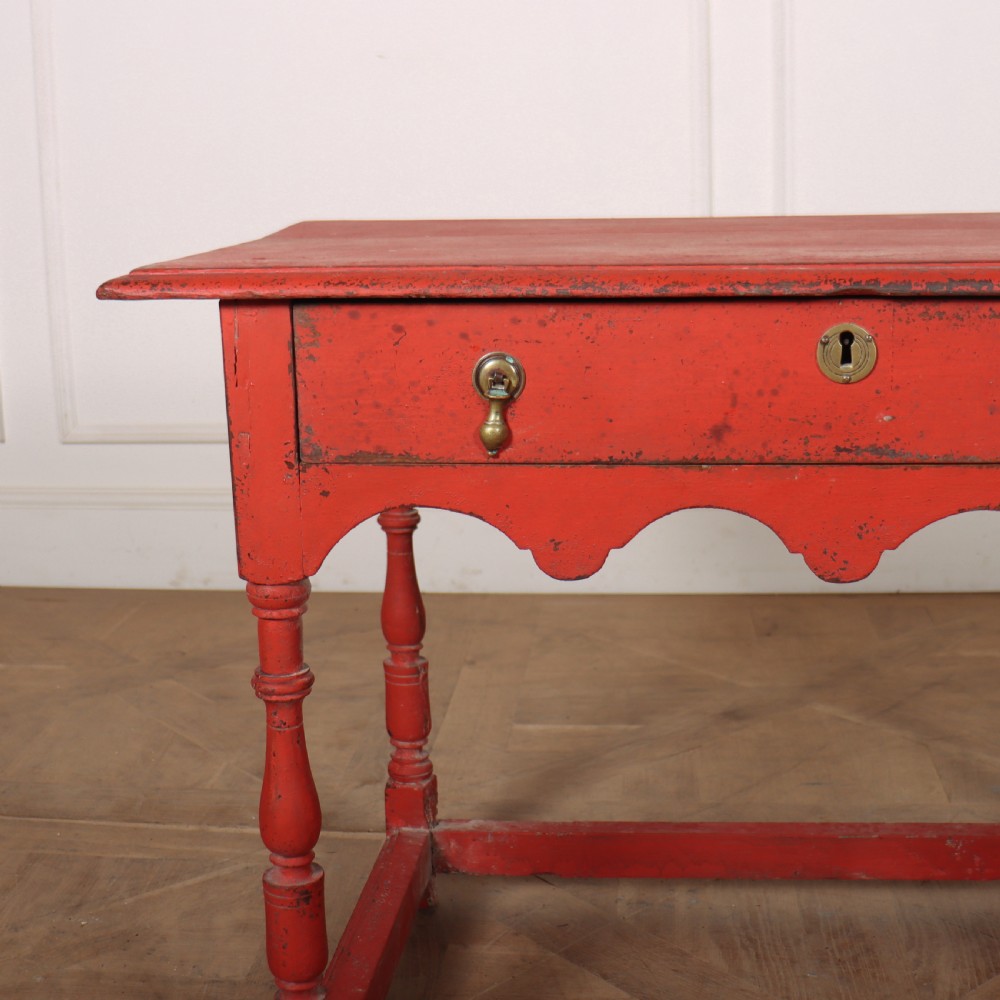 An 18th-century red painted timber side table featuring a single drawer with brass drop handles, a scalloped apron, turned legs, and a full box stretcher. View II