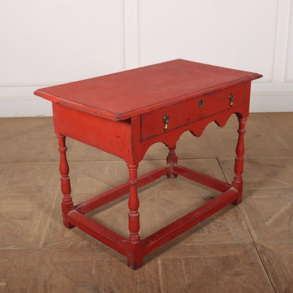 An 18th-century red painted timber side table featuring a single drawer with brass drop handles, a scalloped apron, turned legs, and a full box stretcher. View V