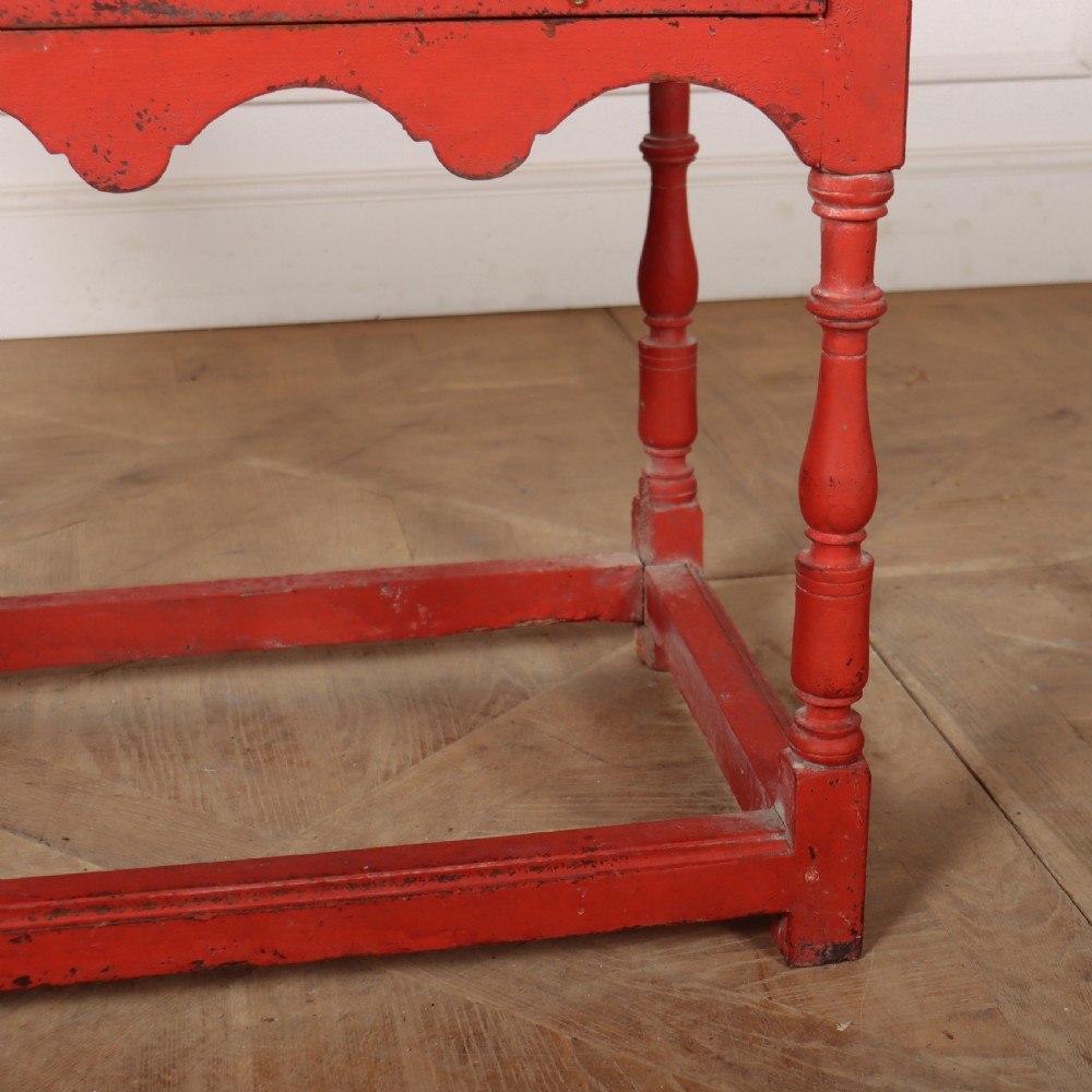 An 18th-century red painted timber side table featuring a single drawer with brass drop handles, a scalloped apron, turned legs, and a full box stretcher. View VI
