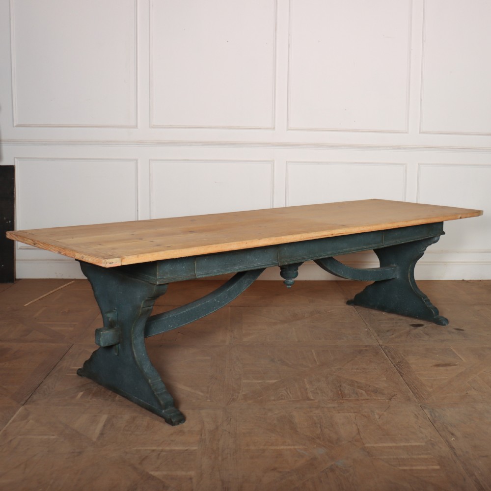 An Italian trestle table featuring a scrubbed natural pine top supported by a dark teal painted timber base with shaped legs and a central stretcher.