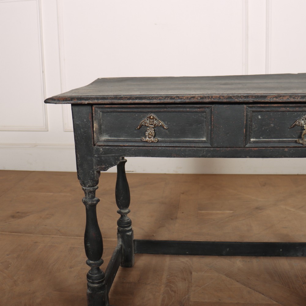 A distressed black painted wooden side table featuring two front drawers with brass handles, turned legs, and a low box stretcher. View II