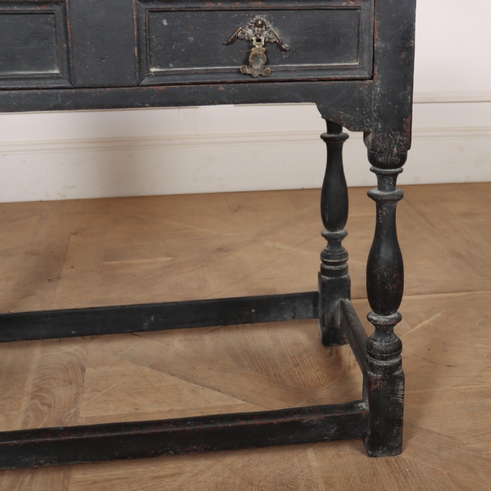 A distressed black painted wooden side table featuring two front drawers with brass handles, turned legs, and a low box stretcher. View IV