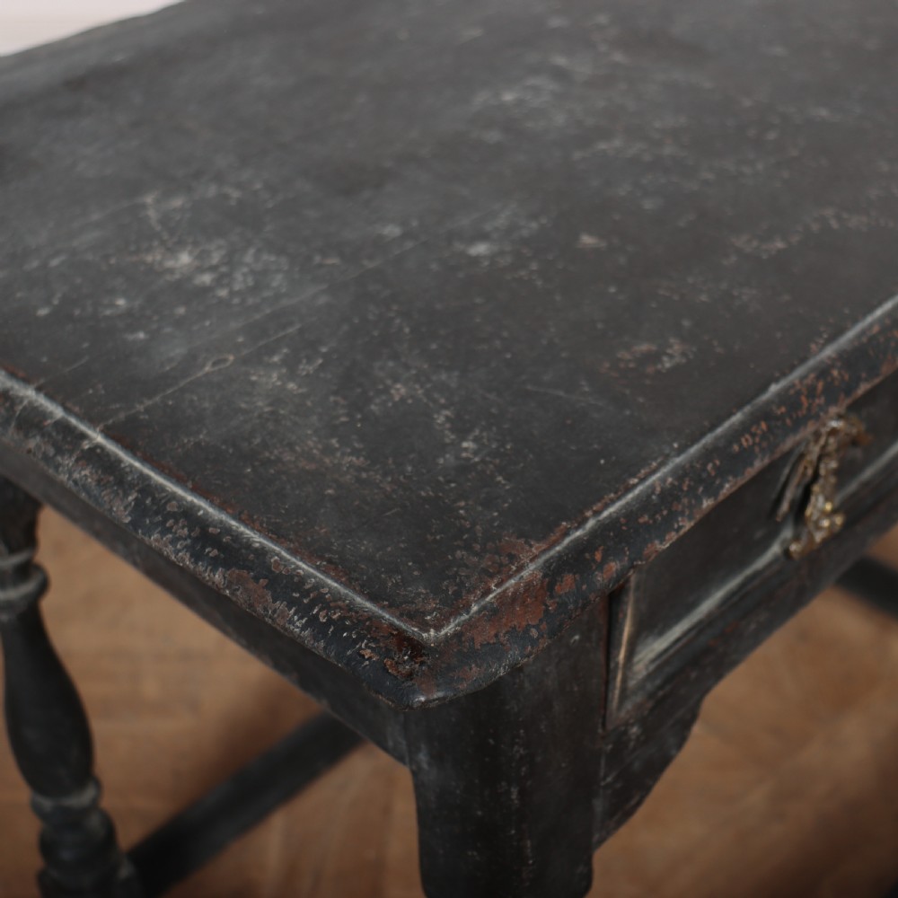 A distressed black painted wooden side table featuring two front drawers with brass handles, turned legs, and a low box stretcher. View VII