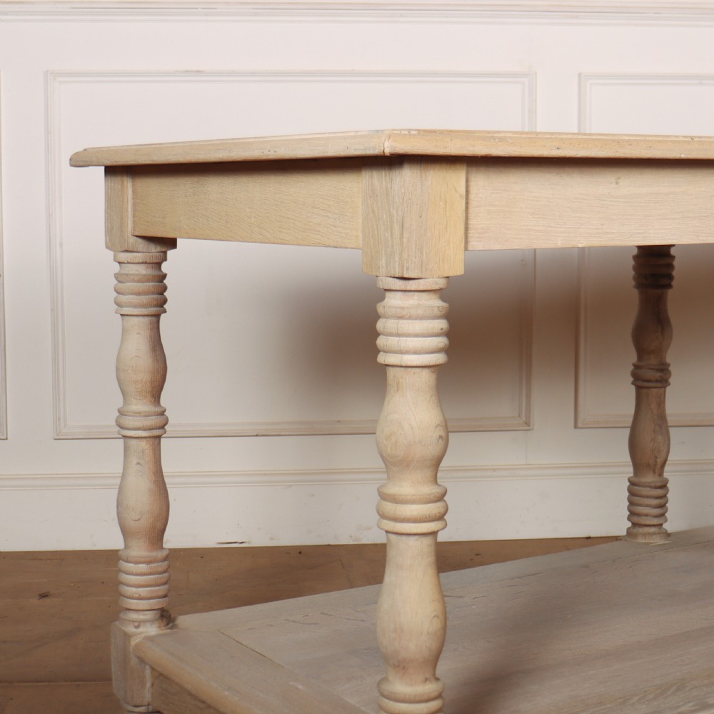 A long bleached oak French drapers table featuring six turned legs and a full-length lower tier shelf. View III