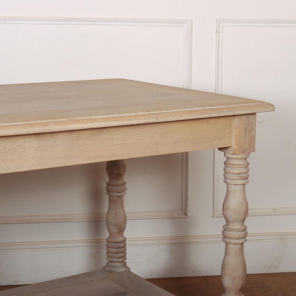 A long bleached oak French drapers table featuring six turned legs and a full-length lower tier shelf. View IV