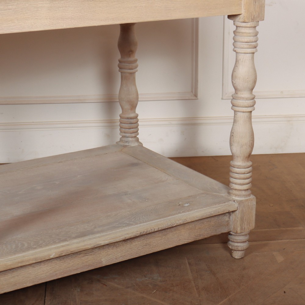 A long bleached oak French drapers table featuring six turned legs and a full-length lower tier shelf. View VI