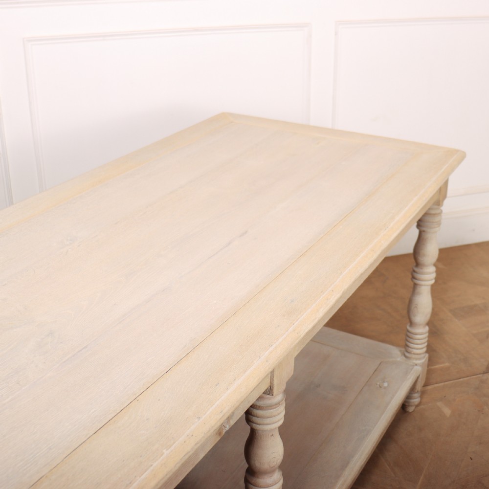 A long bleached oak French drapers table featuring six turned legs and a full-length lower tier shelf. View VII
