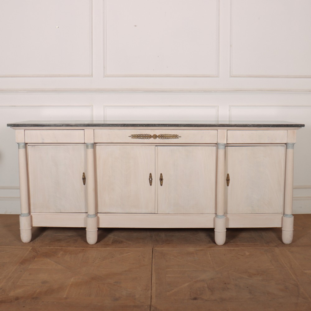 A long French Empire style painted wooden enfilade with four doors, columnar legs, brass escutcheons, and a dark marble top.