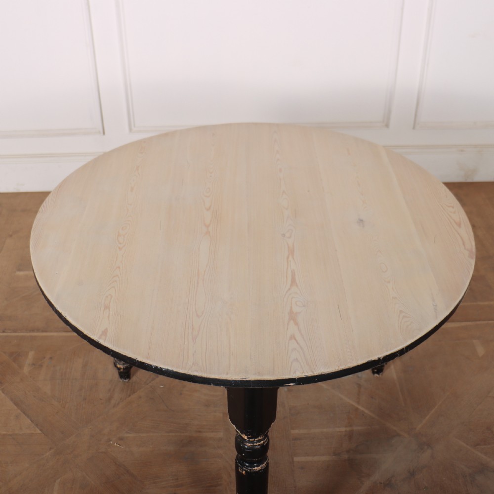 A Welsh pine cricket table featuring a circular scrubbed timber top supported by three turned legs in a distressed black painted finish. View IV