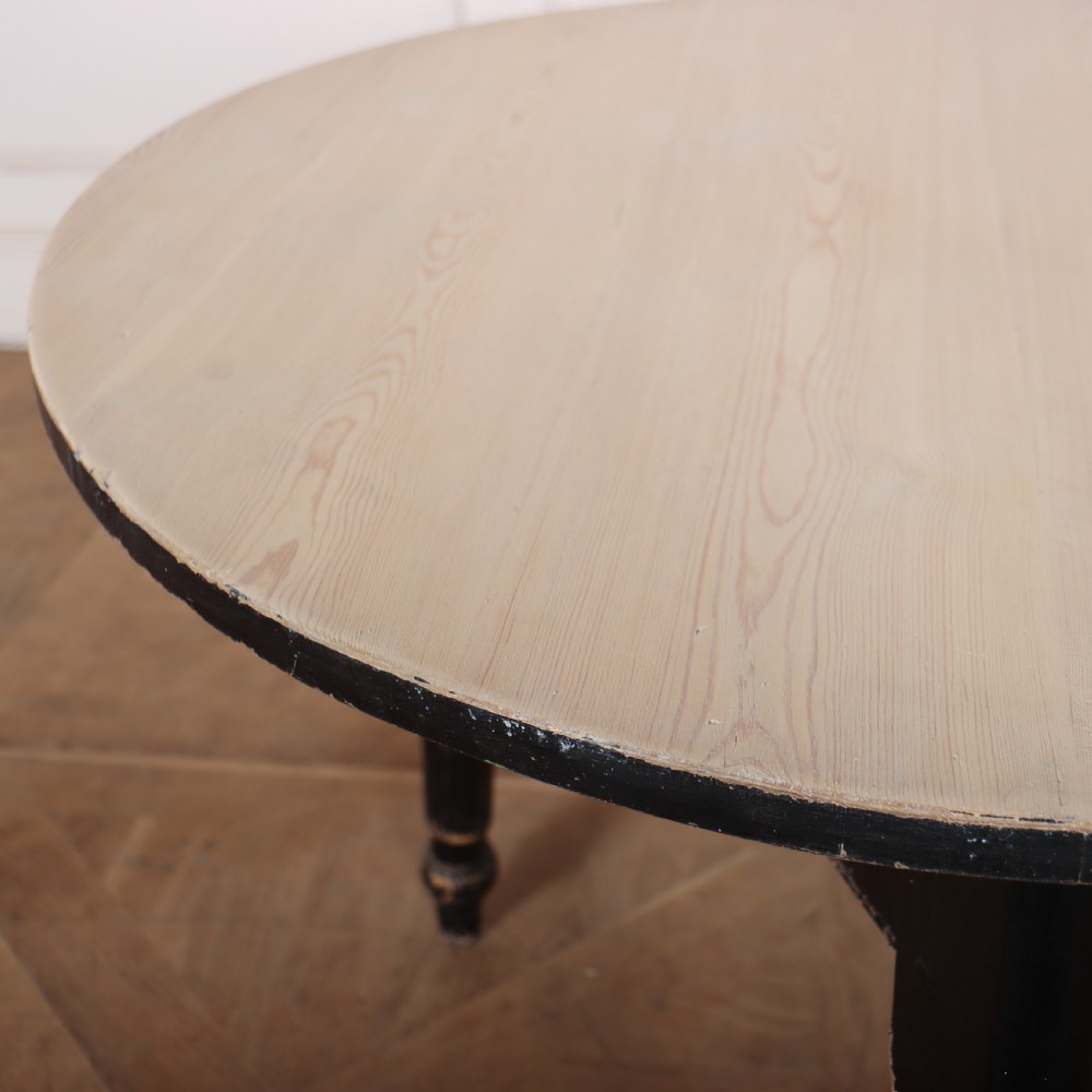 A Welsh pine cricket table featuring a circular scrubbed timber top supported by three turned legs in a distressed black painted finish. View V