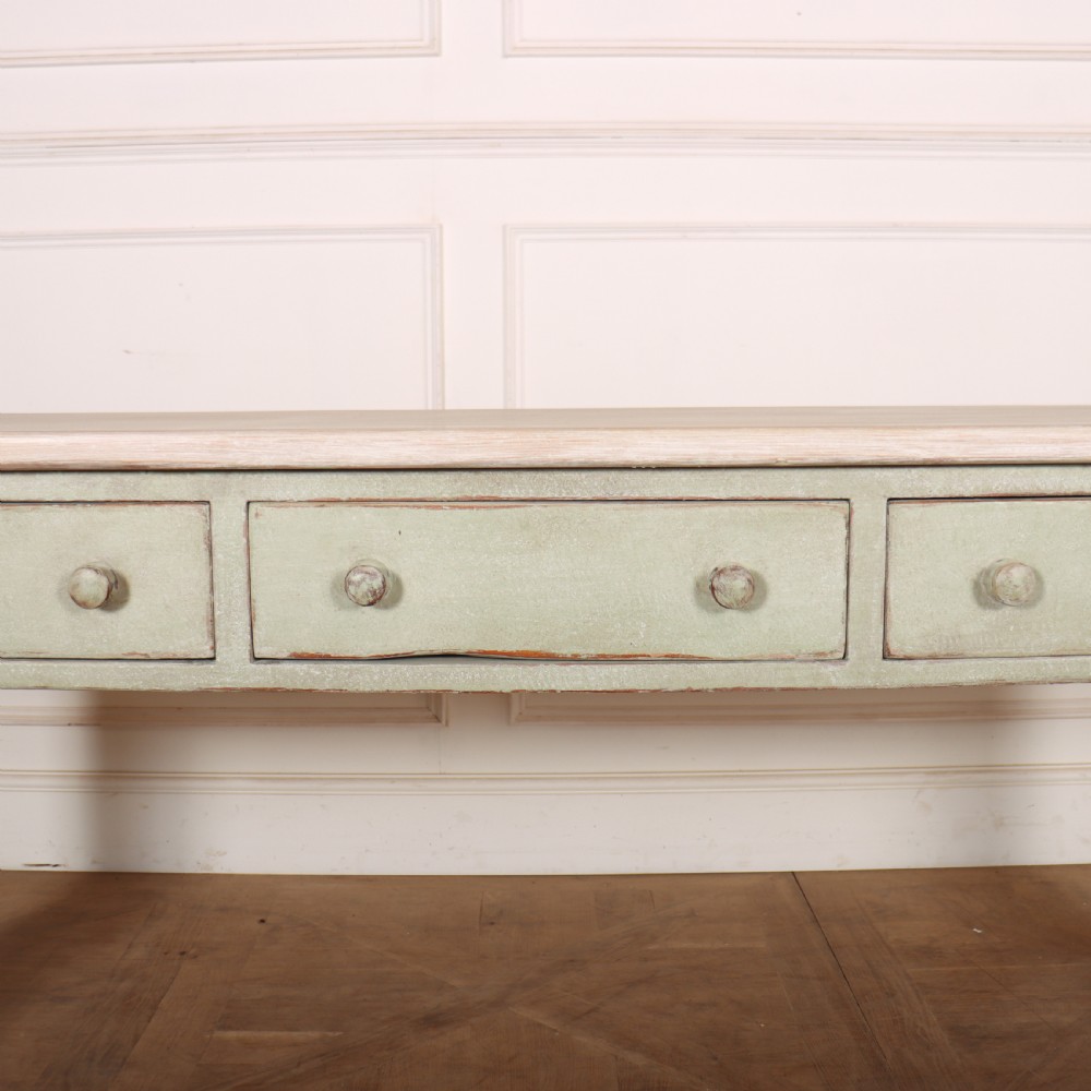 A long narrow wooden console table featuring a pale green painted base, three drawers with wooden turned knobs, and a natural light wood top. View IV