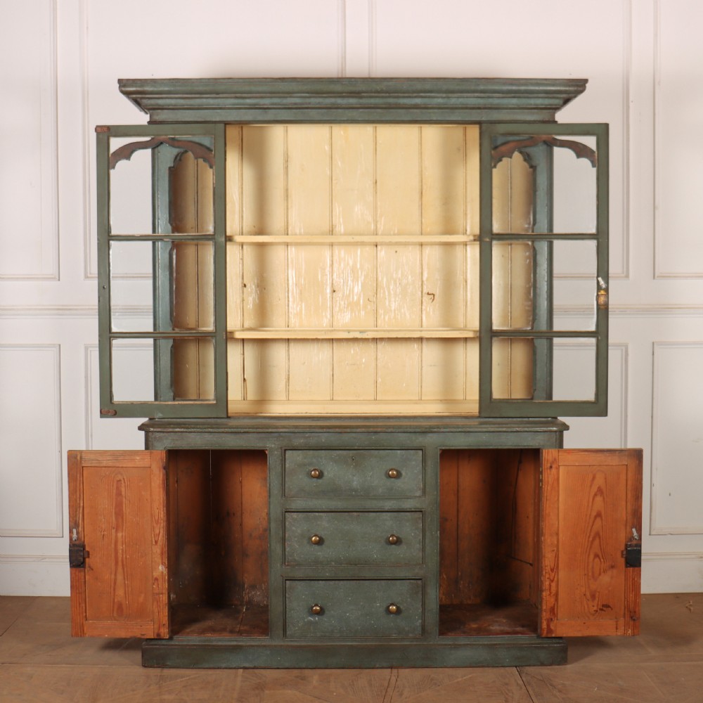 A two-part blue-green painted timber dresser featuring an upper glazed cabinet with gothic arch doors and a lower base fitted with drawers and cupboard doors. View VIII
