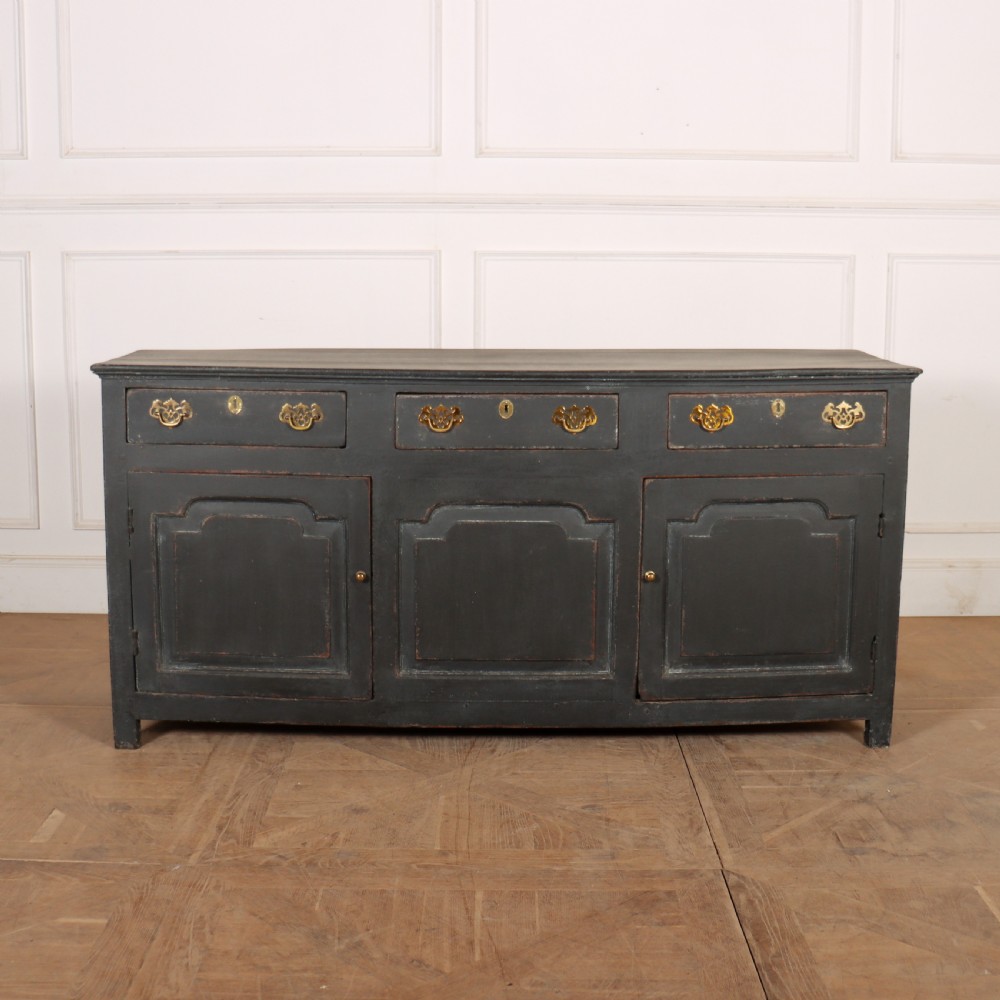 An 18th-century painted wooden dresser base in dark grey featuring three upper drawers with brass swan-neck handles over three cupboard doors with raised panels.