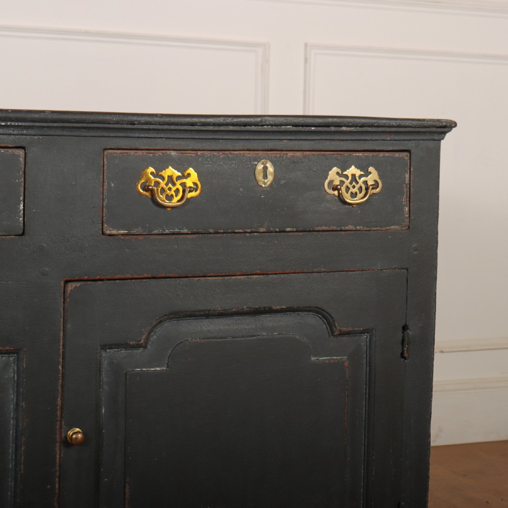 An 18th-century painted wooden dresser base in dark grey featuring three upper drawers with brass swan-neck handles over three cupboard doors with raised panels. View III