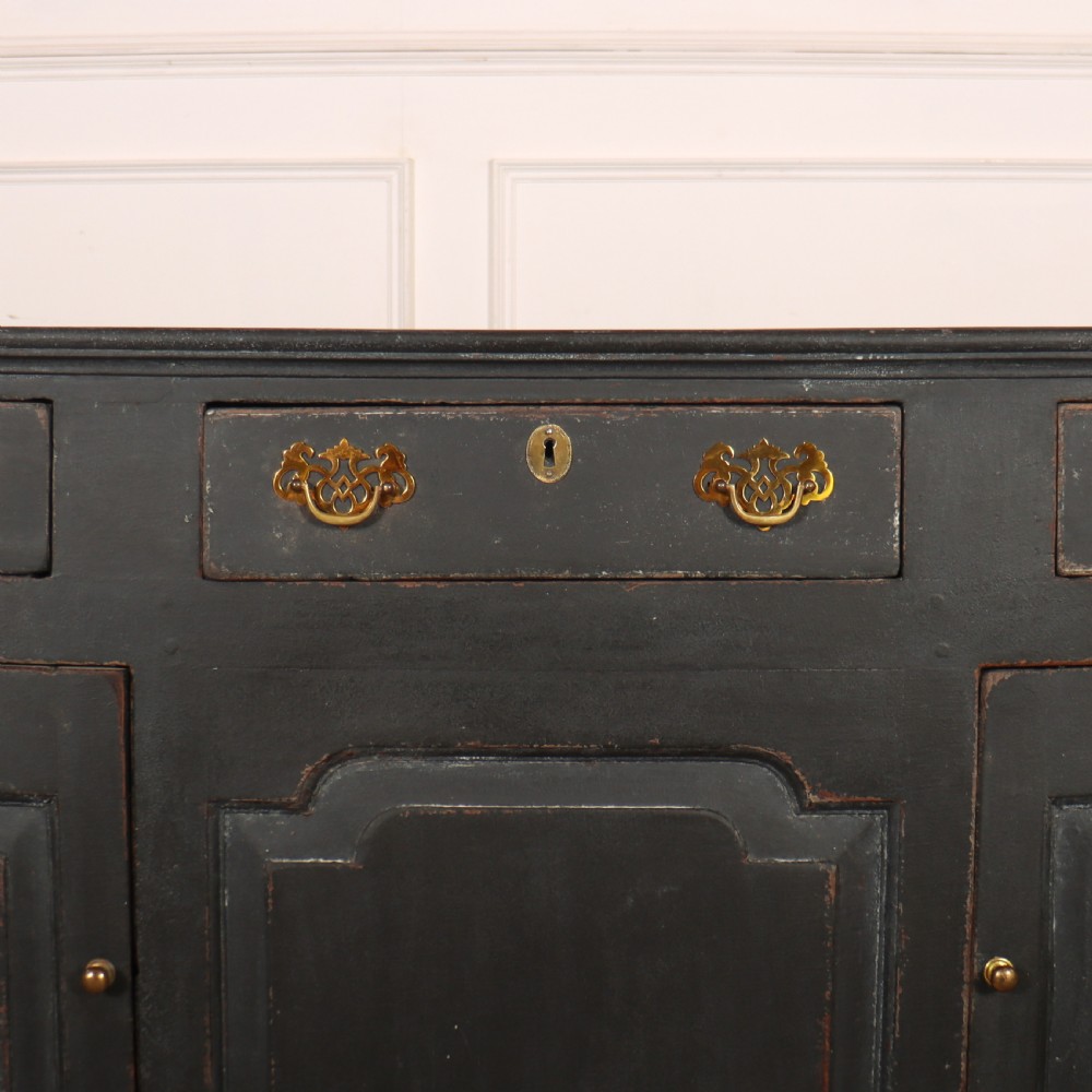An 18th-century painted wooden dresser base in dark grey featuring three upper drawers with brass swan-neck handles over three cupboard doors with raised panels. View IV