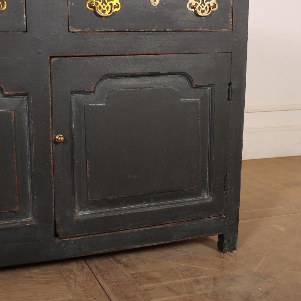 An 18th-century painted wooden dresser base in dark grey featuring three upper drawers with brass swan-neck handles over three cupboard doors with raised panels. View VI