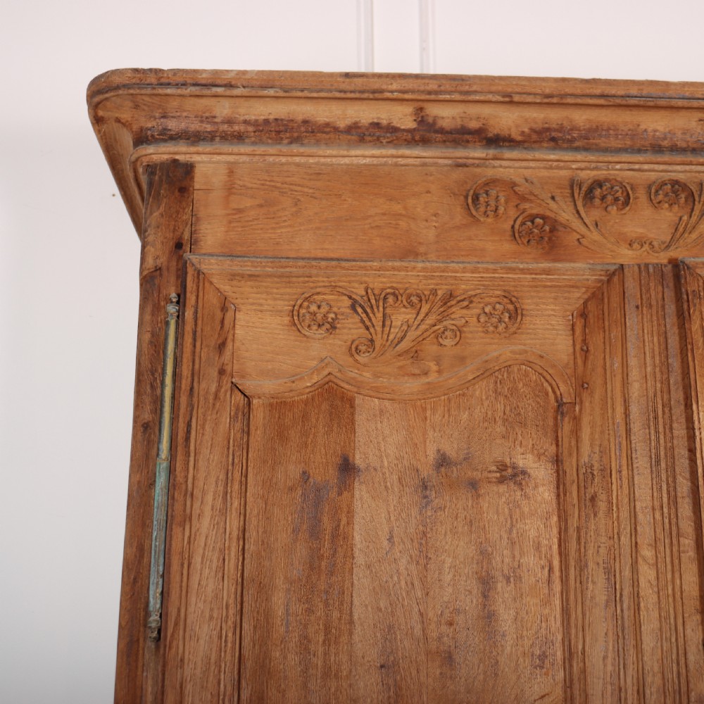 An 18th-century French provincial bleached oak armoire featuring two carved panel doors, long vertical iron hinges, and a moulded cornice. View II