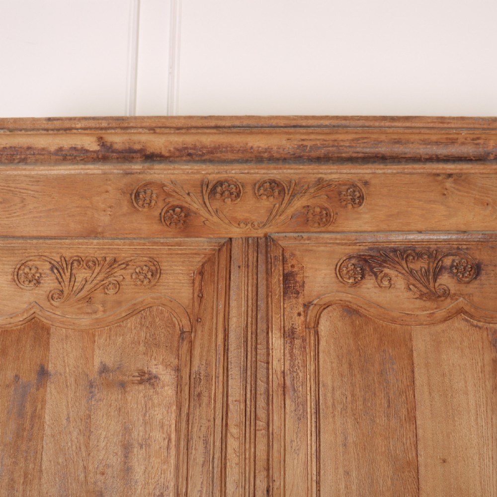 An 18th-century French provincial bleached oak armoire featuring two carved panel doors, long vertical iron hinges, and a moulded cornice. View III