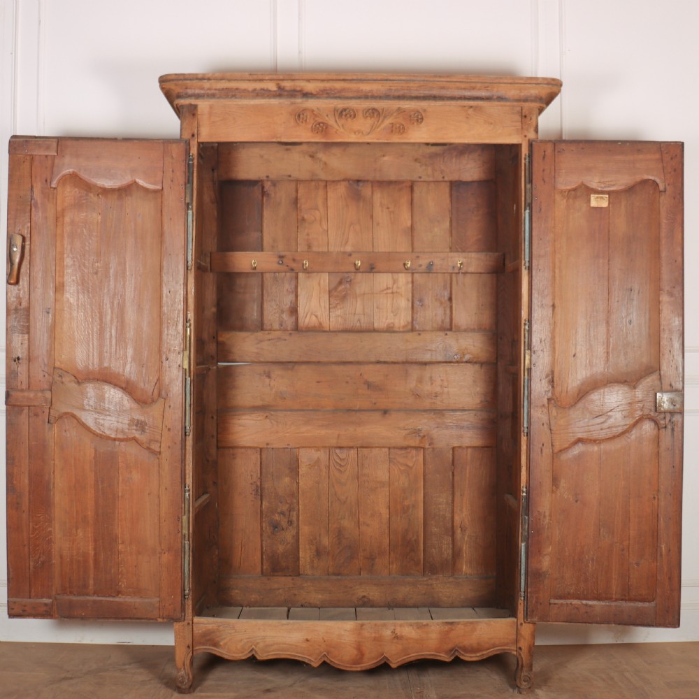 An 18th-century French provincial bleached oak armoire featuring two carved panel doors, long vertical iron hinges, and a moulded cornice. View V