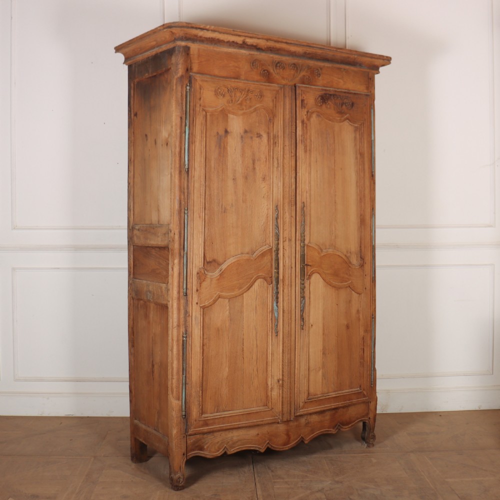 An 18th-century French provincial bleached oak armoire featuring two carved panel doors, long vertical iron hinges, and a moulded cornice. View VII