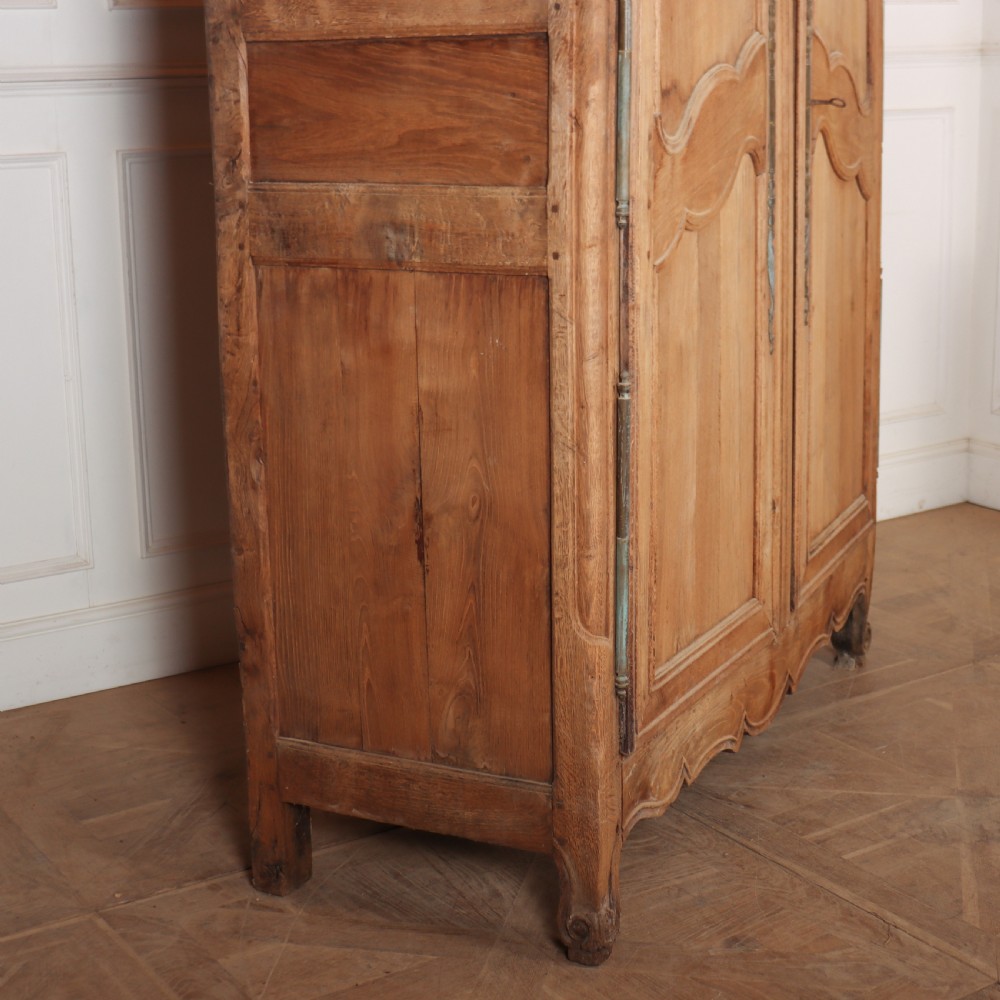 An 18th-century French provincial bleached oak armoire featuring two carved panel doors, long vertical iron hinges, and a moulded cornice. View VIII