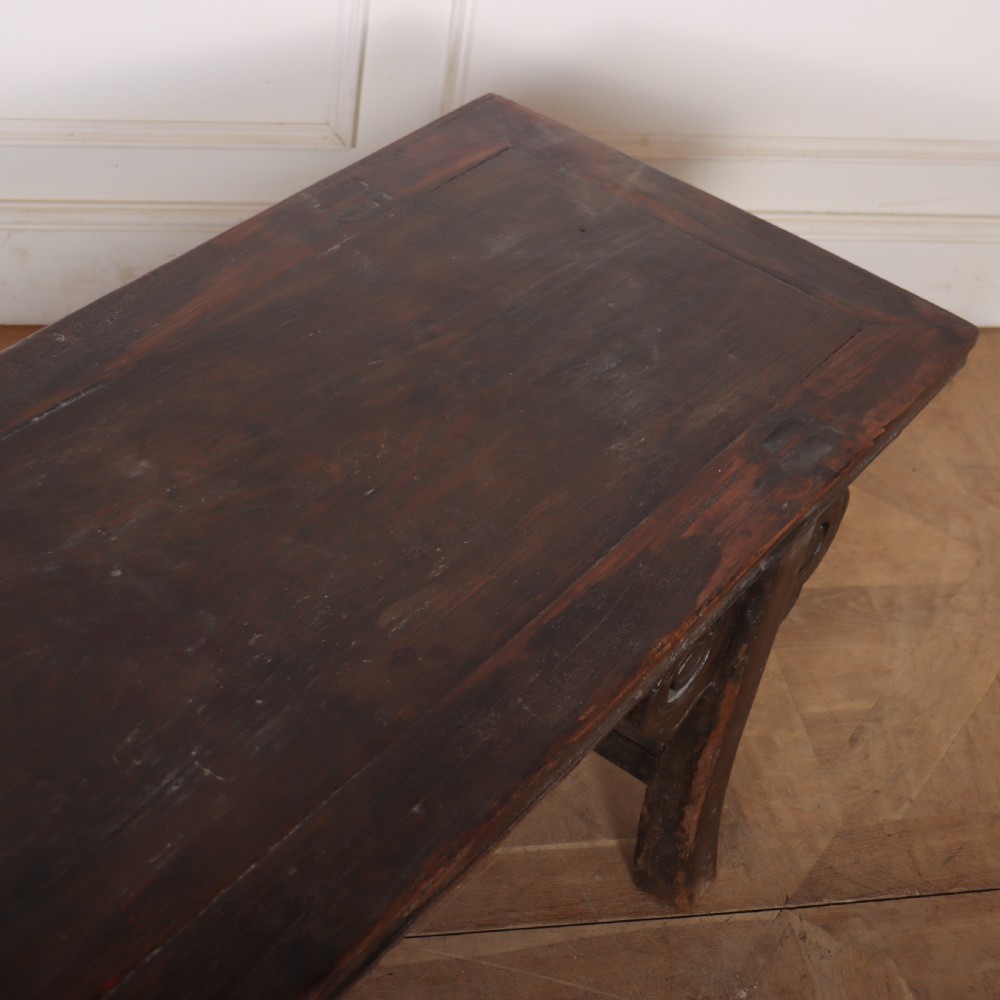 An antique dark brown elm low table featuring an inset panel top, straight legs with transverse stretchers, and carved scroll spandrels. View V