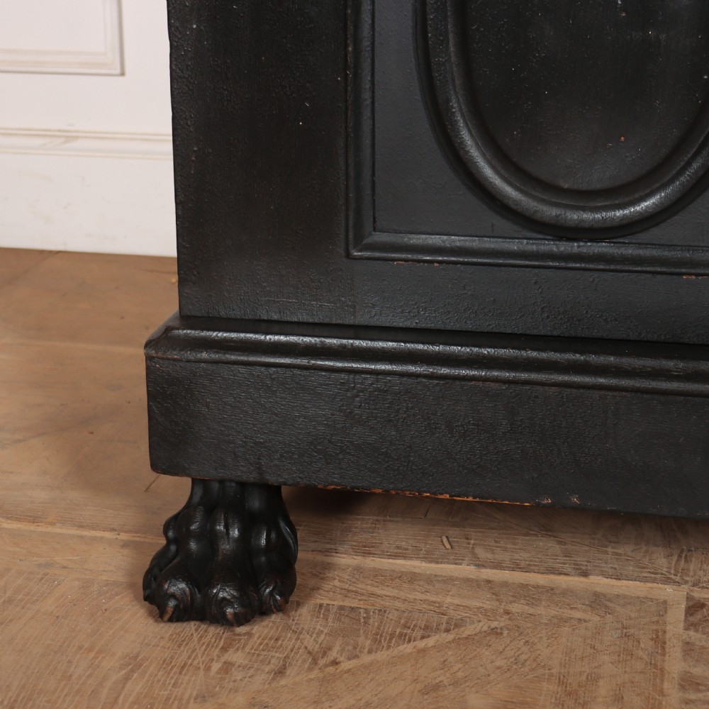 A low black painted wooden credenza featuring three panelled doors with oval mouldings and resting on carved paw feet. View II